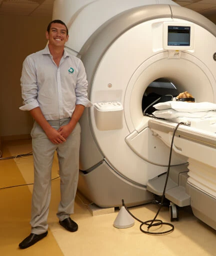 Spencer Howe beside an MRI scanner with an early MRIaudio system