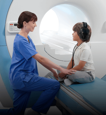 MRI technologist assisting young MRI patient with headphones and music